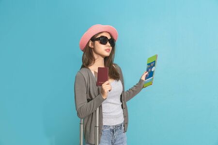 Smiling asian woman traveler holding passport with passport on blue background.の写真素材