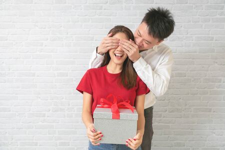 Young couple man and woman at home offering to gifts for lover's valentine day.の写真素材