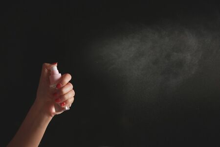 Hand using a spray, isolated on black background.の写真素材