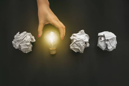 Female hand holding light bulb on black background. New idea conceptの写真素材