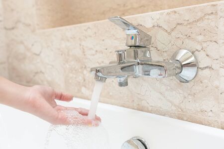 Woman hand taking a bath at home checking temperature touching water with hand.の写真素材