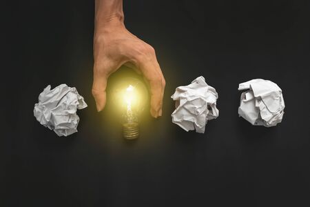 Female hand holding light bulb on black background. New idea concept の写真素材