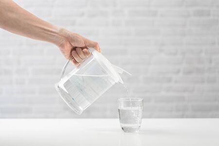 Woman's hand pouring water from pitcher into a glass. Healthy Lifestyle conceptの写真素材