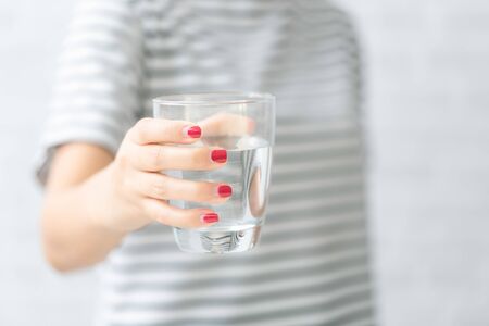 Woman's of hand holding a glass of water on white background.の写真素材