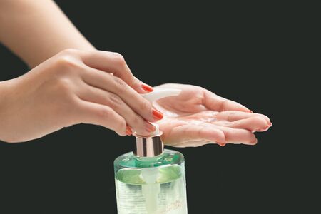 Hands female using wash hand sanitizer gel pump dispenser.