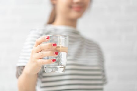 Woman's of hand holding a glass of water on white background.の写真素材