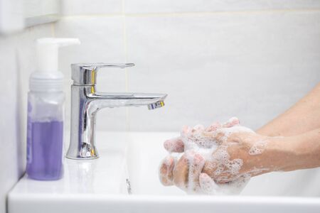Woman hands use soap and washing her hands under the faucet. Hygiene conceptの写真素材
