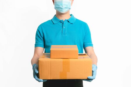 Delivery man employee in blue shirt uniform face mask gloves hold empty cardboard box on blue background. Coronavirus virus 2019 conceptの写真素材
