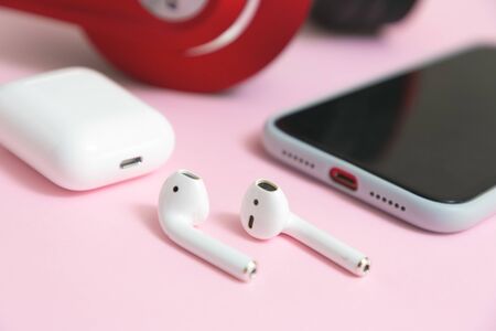 Close-up Wireless earphones, mobile phone and charging case on pink background.の写真素材