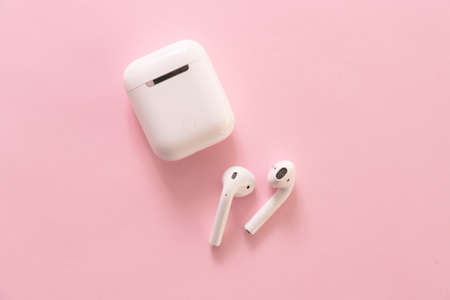 NAKHONRATCHASIMA, THAILAND - APRIL 10, 2020: Apple AirPods wireless Bluetooth headphones and charging case for Apple iPhone on a pink background.のeditorial素材