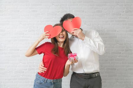 Together forever. Portrait of positive romantic couple man hug paper heart his sweetheart woman.の写真素材