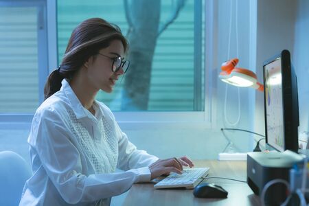 Young asian female in glasses using computer, communicates on internet with customer in home. E learning conceptの写真素材
