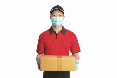 Delivery man employee in red shirt uniform face mask gloves hold empty cardboard box on white background. clipping pathの写真素材