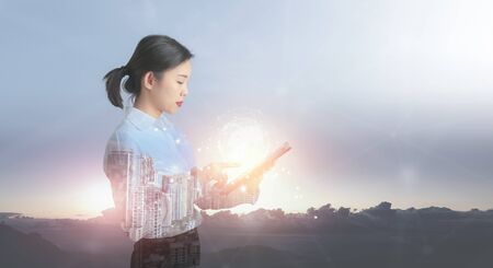 Businesswoman holding with tablet pc against high tech overlooking the view of landscape.の写真素材