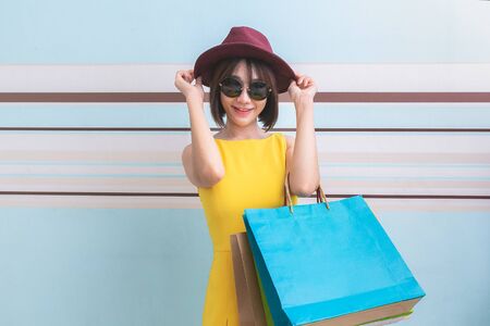 Portrait of asian beautiful girl wearing yellow dress and sunglasses holding shopping bags.の写真素材