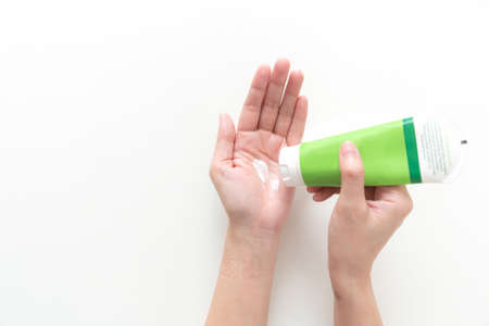 Woman hand holding cream tube and applying moisturizer cream on her beautiful hands. top viewの写真素材