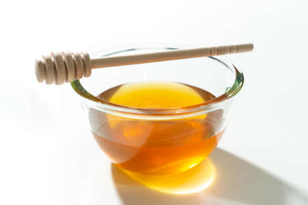 Fresh honey bee in bowl with dipper on white background.の写真素材