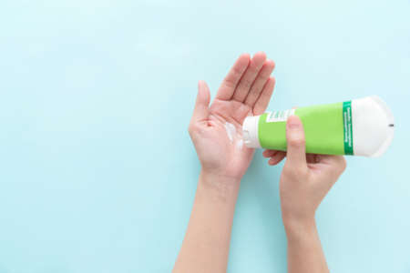 Woman hand holding cream tube and applying moisturizer cream on her beautiful hands. top viewの写真素材