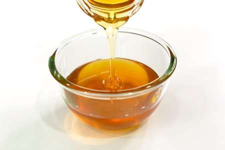 Pour Fresh honey bee in bowl on white background.の写真素材