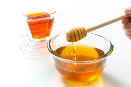 Fresh honey bee in bowl on white background. honey teaの写真素材