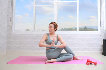 Young attractive woman practicing yoga, doing Half lord of the fishes exercise with namaste.の写真素材