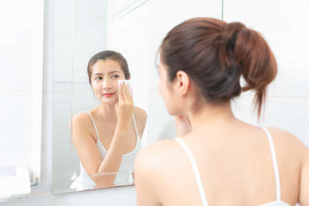 Beautiful Asian Woman applying cosmetic cream in bathroom.の写真素材