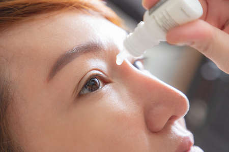 Closeup view of young asian woman applying eye drop. artificial tears.の写真素材