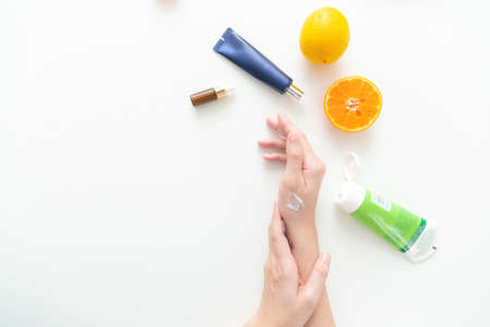 Woman hand holding cream tube and applying moisturizer cream on her beautiful hands. top viewの写真素材