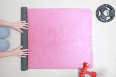 Hands of Woman rolling her Yoga mat after a workout. top view, copy spaceの写真素材