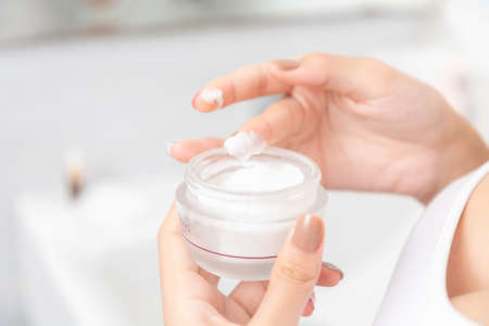 A woman holds a moisturizer in her hand and her skin and wrinkle from impurities.の写真素材