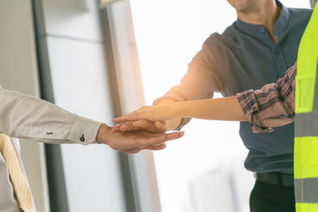 Businessmen and engineers stack hands of teamwork join together to build successful projects....
