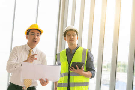 Professional two engineers are discussing the new project. The senior man is standing and holding the blueprint.の写真素材