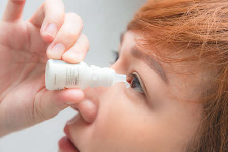 Closeup view of young asian woman applying eye drop. artificial tears.の写真素材