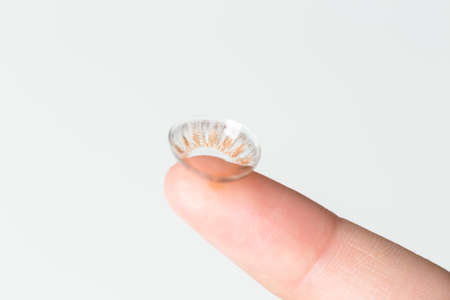 Finger with contact lens on blurred background.の写真素材