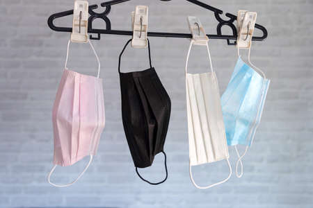Hang a masks on a black hanger on brick wall background.