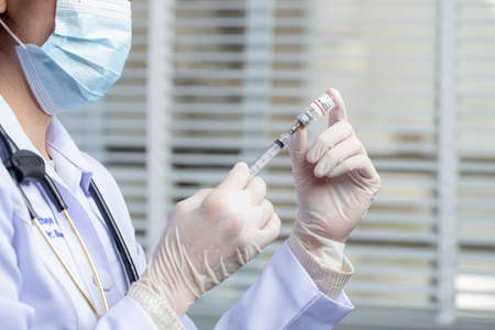Asian medical worker, nurse in mask, hold syringe with vaccine.の写真素材