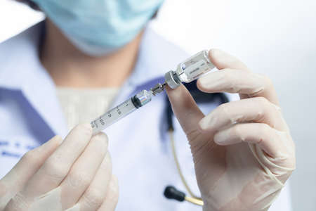 Asian medical worker, nurse in mask, hold syringe with vaccine.の写真素材
