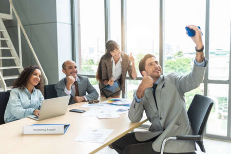 Happy friends business partners are making selfie photo, sitting in the office room.の写真素材