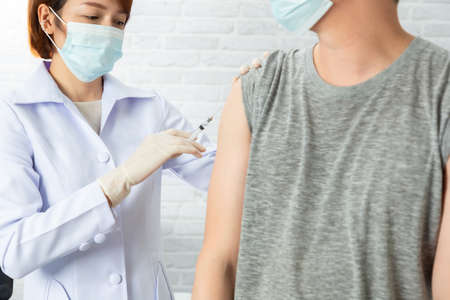 Doctor wearing protective medical mask for protection from virus disease with syringe doing...