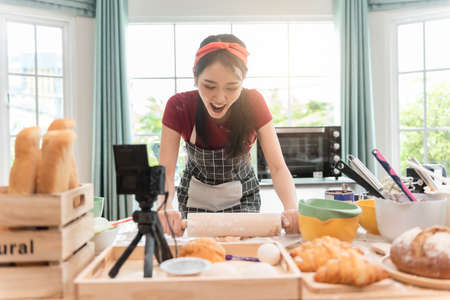 Happy woman use fresh natural products flour milk eggs kneading dough for pastries cookies by hands at modern kitchen.の写真素材