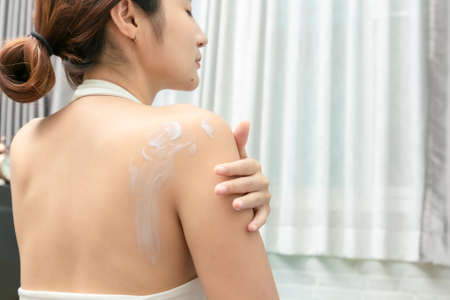Young asian woman using cream after shower for body care, skin care products concept.の写真素材