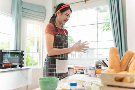 Happy woman use fresh natural products flour milk eggs kneading dough for pastries cookies by hands at modern kitchen.の写真素材