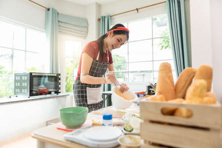 Happy woman use fresh natural products flour milk eggs kneading dough for pastries cookies by hands at modern kitchen.の写真素材