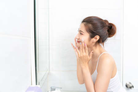 Young Asian woman washing her face in bathroom.の写真素材