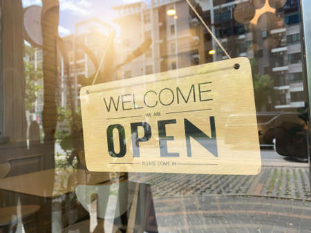 Text on  sign "Welcome we're OPEN" in cafe.の写真素材