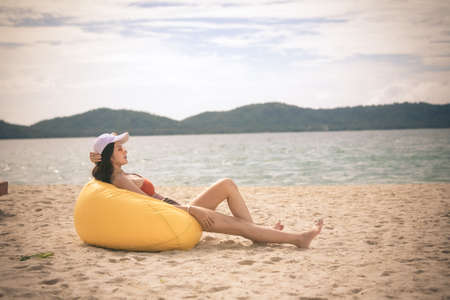 Asian woman with hat relaxing and arm up on chair beach in Thailand. Summer beach vacation concept.の写真素材