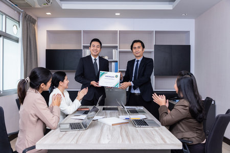 Welcome to our team of young modern men in smart casual wear shaking hands while working in the...