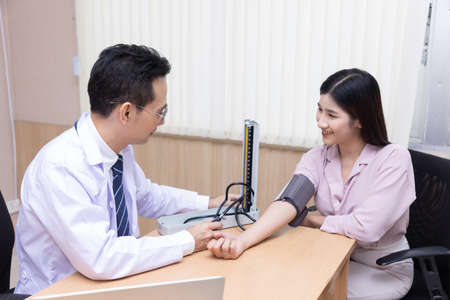 Doctor measures the pressure of the patient during a medical examination and discuss in the...