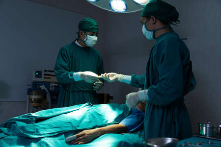 Assistant hands out instruments to surgeons during operation.の写真素材