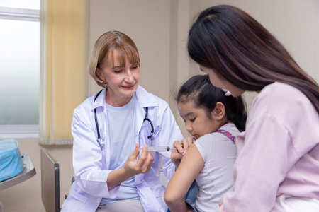 Pediatrician doctor doing vaccination of a little girl in hospital.の写真素材